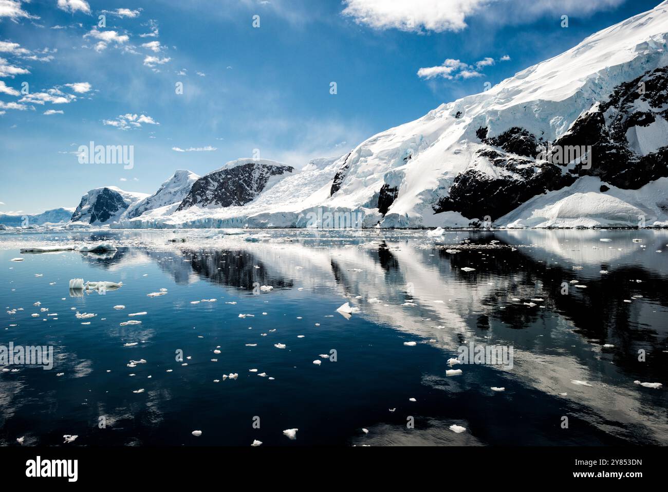 Glaciers et montagnes du port de Neko Antarctique // PORT DE NEKO, Antarctique — les montagnes escarpées et les glaciers entourant le port de Neko créent des reflets parfaits dans les eaux exceptionnellement calmes de l'Antarctique. Le paysage polaire immaculé de pics couverts de glace et d'affleurements rocheux miroirs avec une clarté exceptionnelle dans la surface vitreuse du port. Cet endroit éloigné de la péninsule Antarctique met en valeur le spectaculaire terrain glaciaire de la région. Banque D'Images