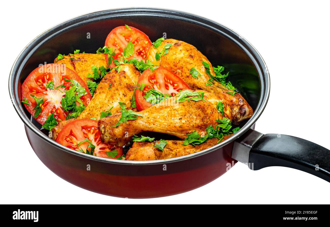 Cuisses de poulet délicieusement assaisonnées avec tomates et persil dans une poêle. Banque D'Images