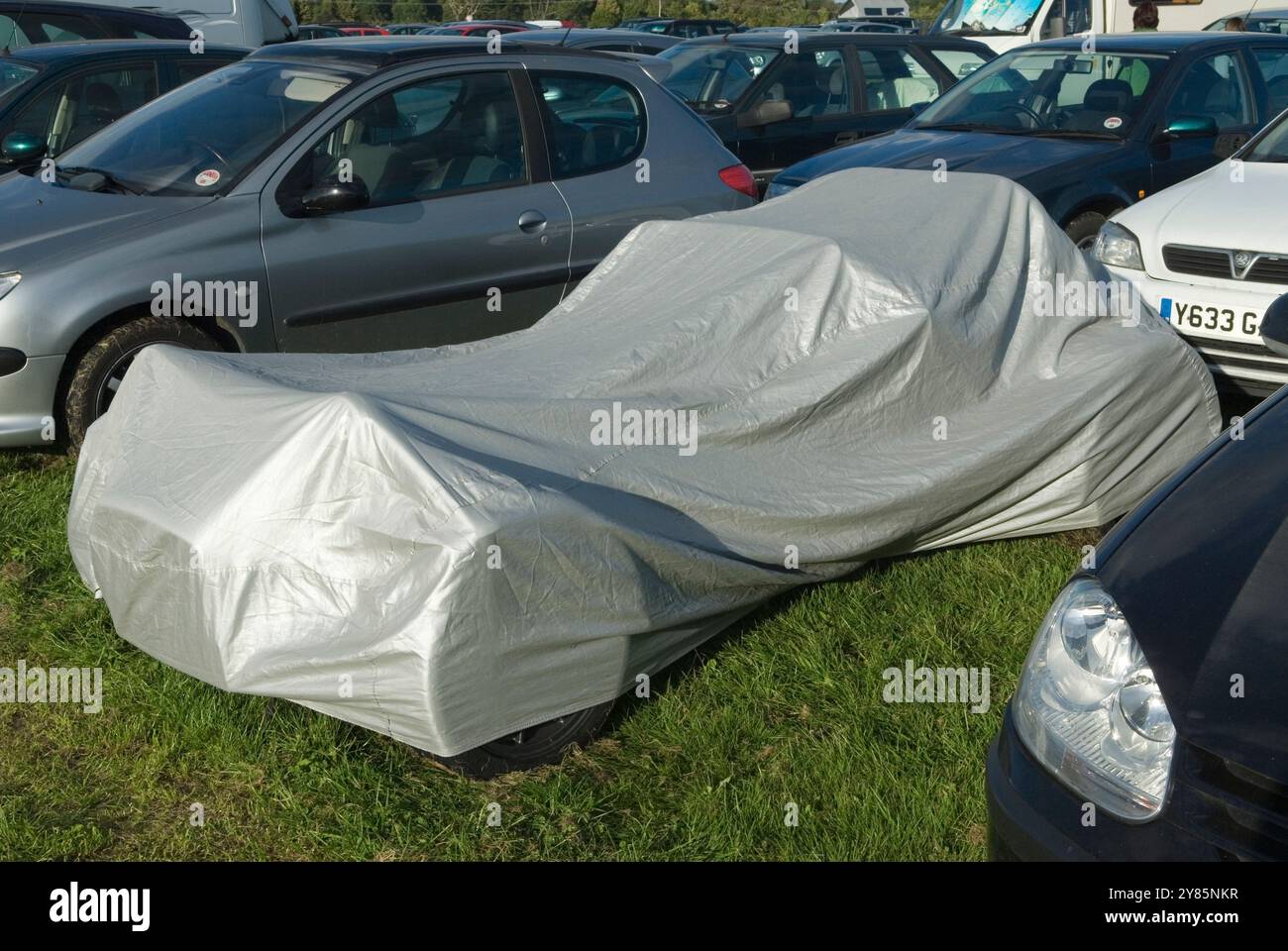 Voiture de sport sous une housse de protection garée dans un parking plein de voitures. Campagne événement et le propriétaire était secret sur sa voiture! ANNÉES 2013 2010 ROYAUME-UNI HOMER SYKES Banque D'Images