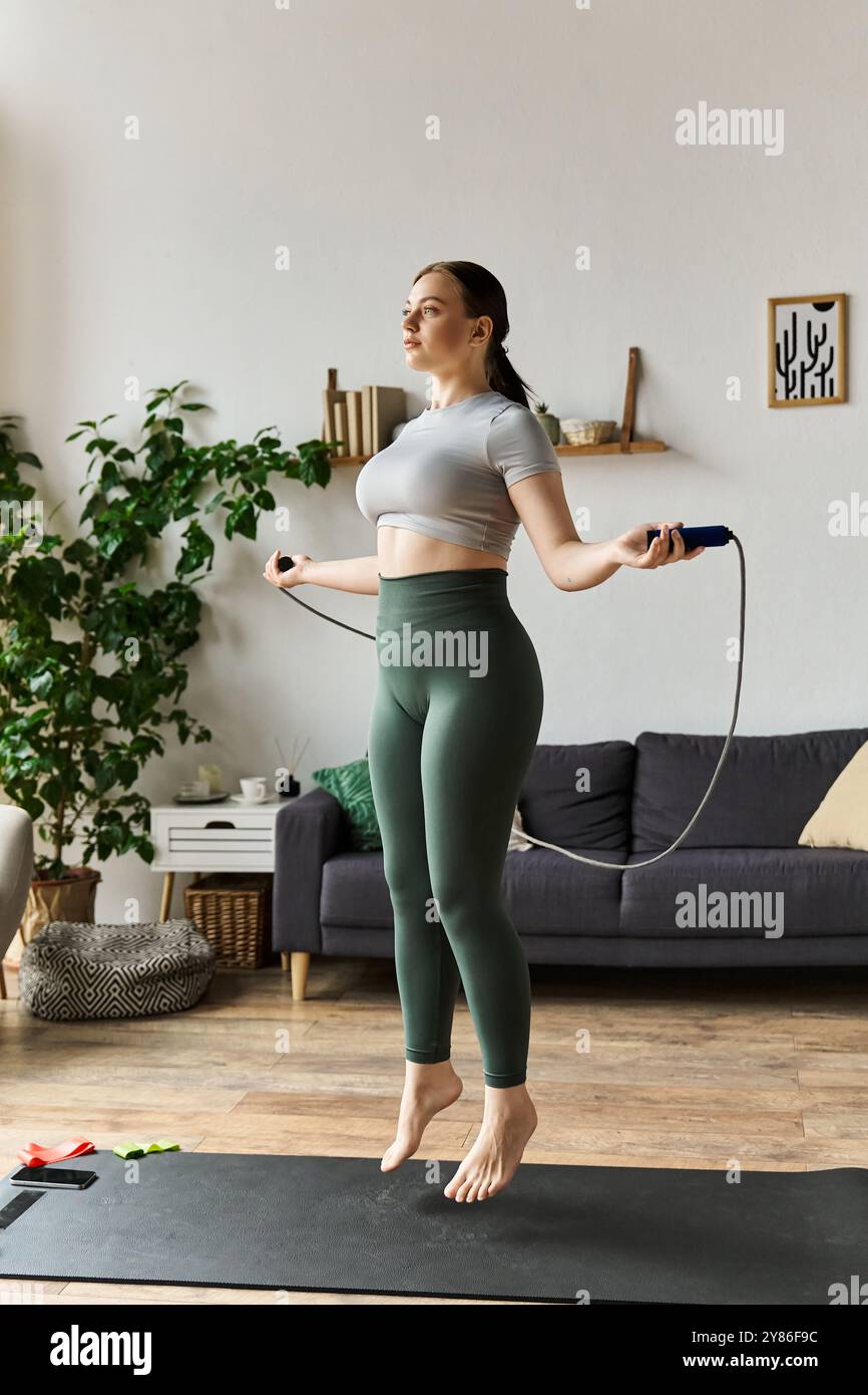 Une femme sportive exerce énergiquement à la maison, sautant à la corde dans une tenue athlétique confortable. Banque D'Images