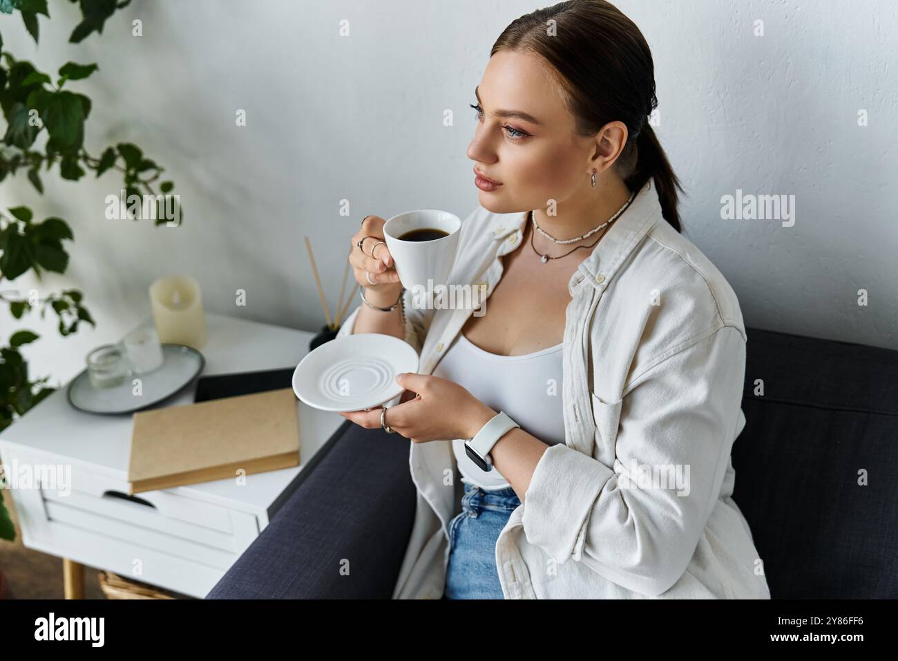 Une jeune femme sirote un café à la maison dans un environnement confortable et accueillant. Banque D'Images