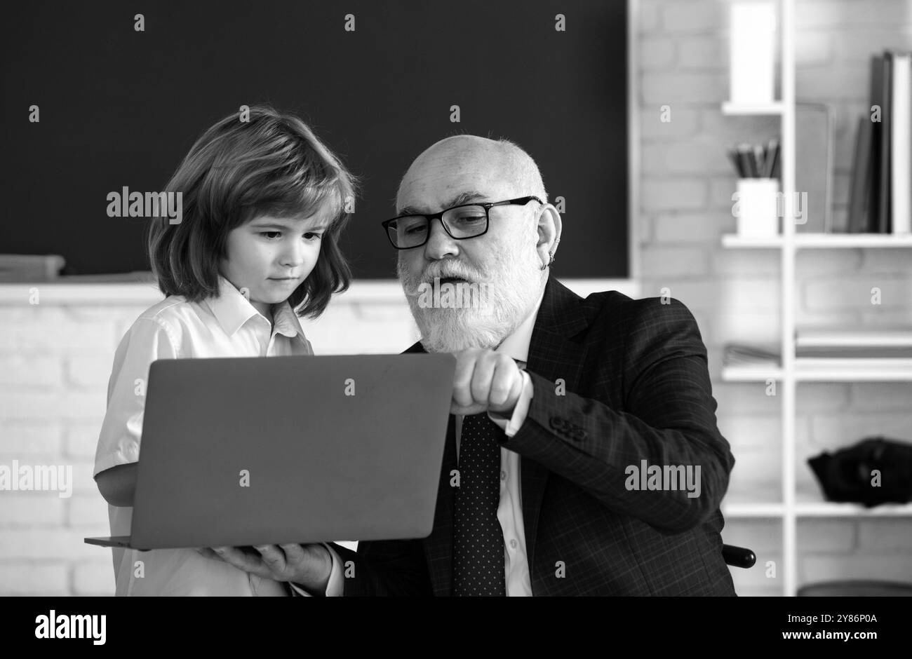 Leçons en ligne. L'enseignant de l'école aide à apprendre. Un élève qui apprend en classe. Éducation, enseignement. Leçon enfant élève. Banque D'Images