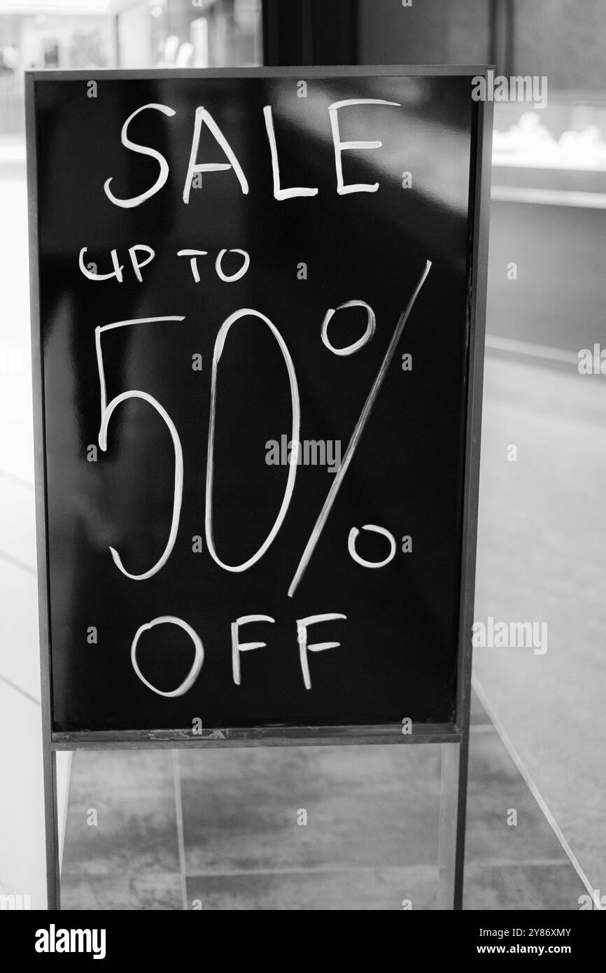panneau d'affichage de 50 % de vente. Solde jusqu'à 50 précent off texte sur un stand de tableau d'affichage à l'intérieur d'un magasin de vêtements populaire pendant la vente de fin d'année de saison. Conce Banque D'Images