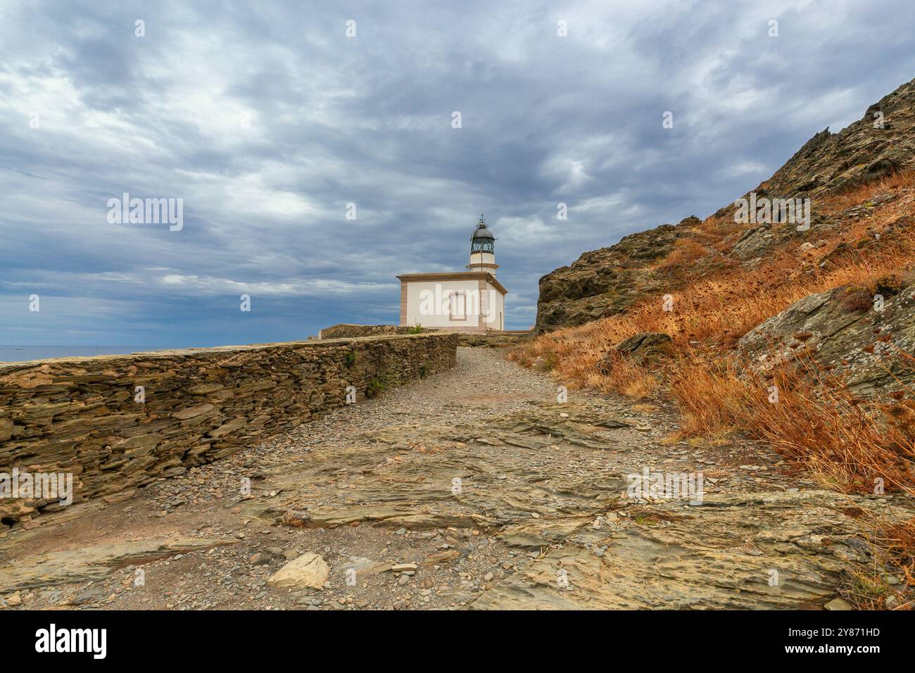 Phare de Cala Nans sur des rochers sous ciel nuageux avec une mer orageuse en arrière-plan, Espagne, Catalogne Banque D'Images