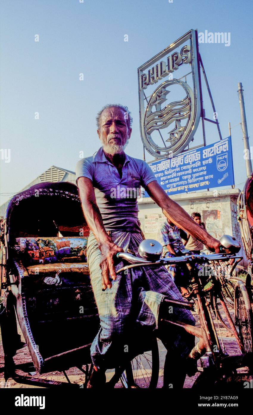 Bangladesh, Dacca, homme plus âgé sur un trishaw devant le logo Philips. Banque D'Images