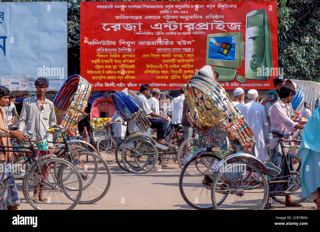À Dhaka, au Bangladesh, les rickshaws passent un panneau publicitaire pour le programme informatique Windows. Banque D'Images
