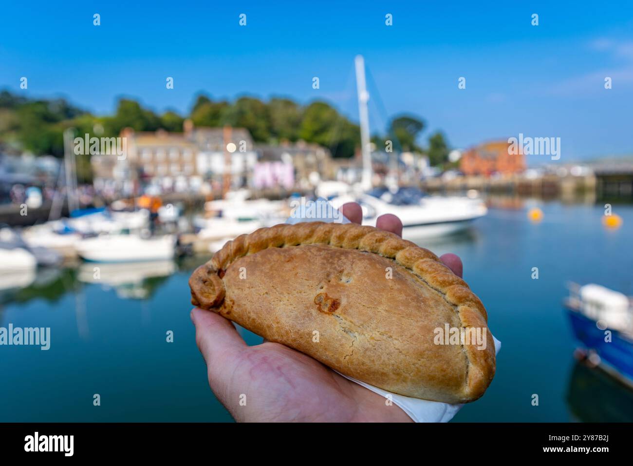 Délicieuse pâte de Cornouailles à la main, Harbour of Padstow en arrière-plan Banque D'Images