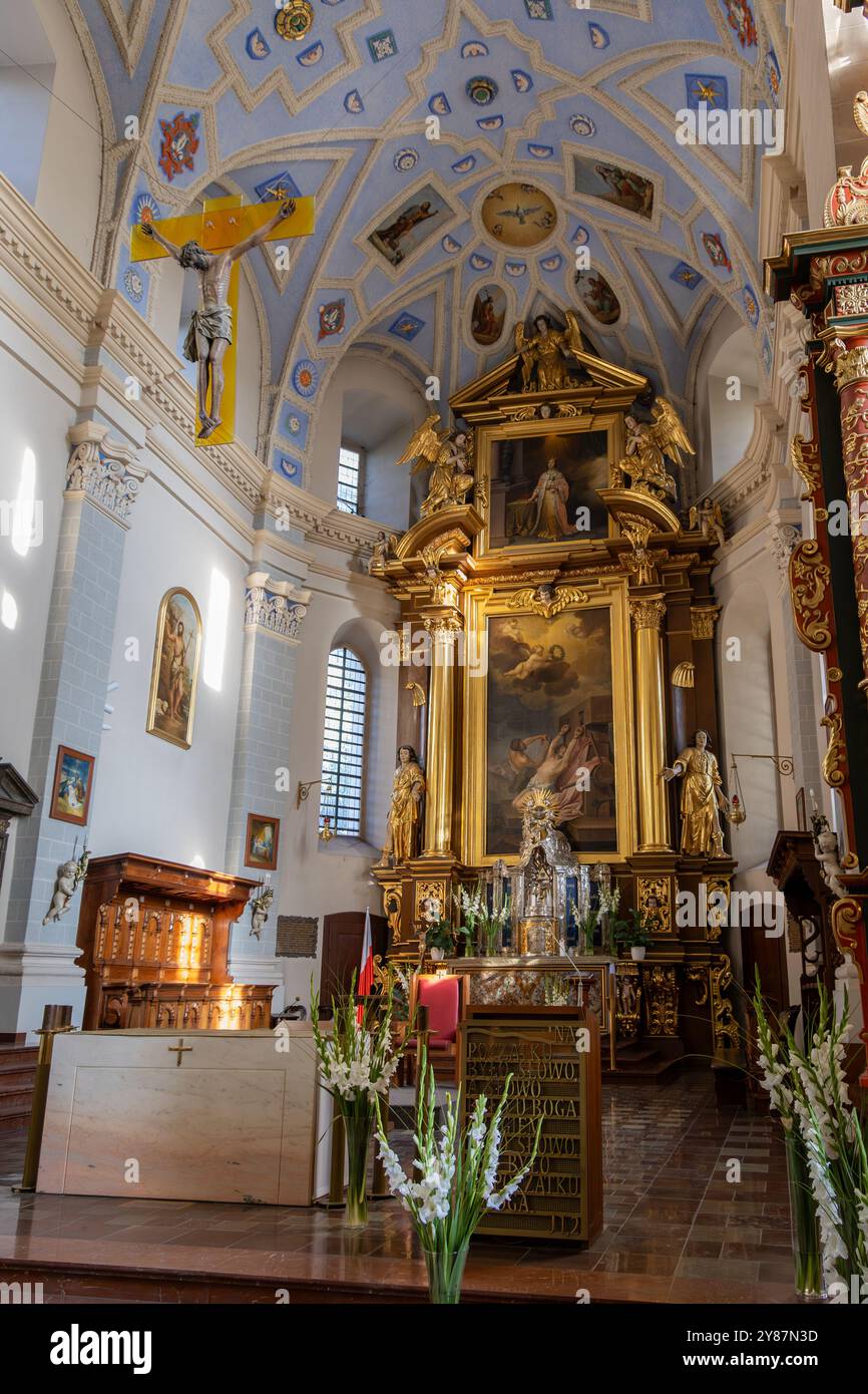 Explorez l'intérieur magnifique d'une église baroque avec un autel doré orné, un plafond voûté avec des motifs bleus et dorés, et des œuvres d'art religieux Banque D'Images