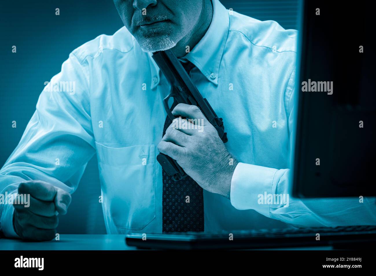 Homme d'affaires tient une arme sous son menton tout en étant assis à son bureau, transmettant la pression intense et le désespoir qui peuvent accompagner la baguette de l'entreprise Banque D'Images