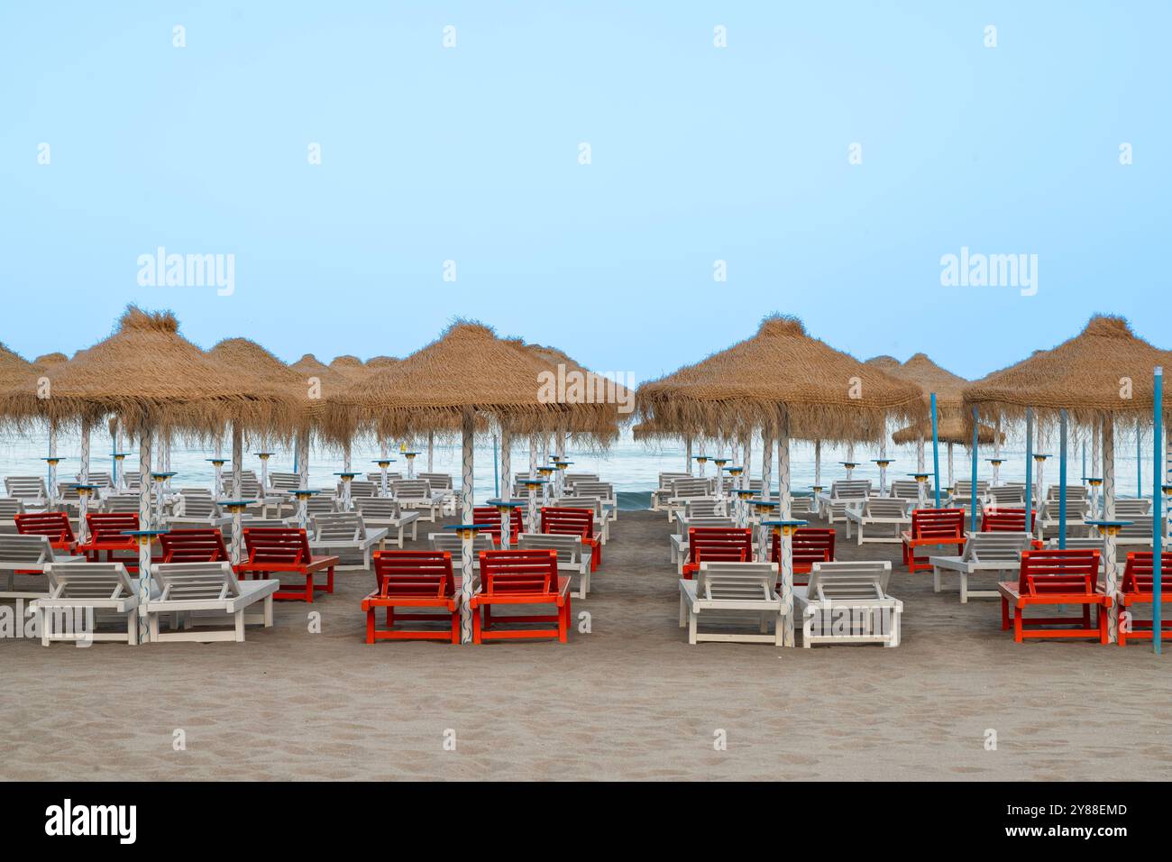 Parasols palmiers et chaises longues sur la plage de la mer Méditerranée en Espagne. Banque D'Images