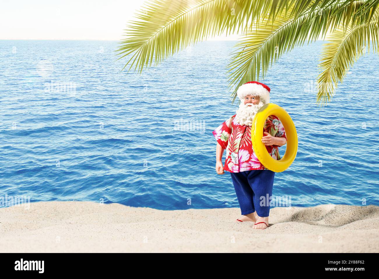 Père Noël avec anneau gonflable sur la plage sous le palmier. Vacances de Noël, climat tropical. Banque D'Images