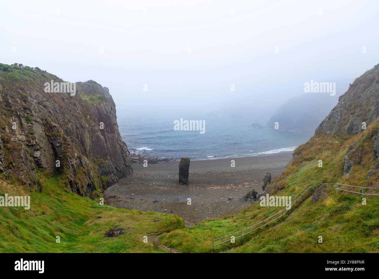 Paysage marin brumeux à la plage de Trá-na-mBó, Bunmahon, Irlande – scène de plage tranquille avec des rives rocheuses et des vagues douces Banque D'Images