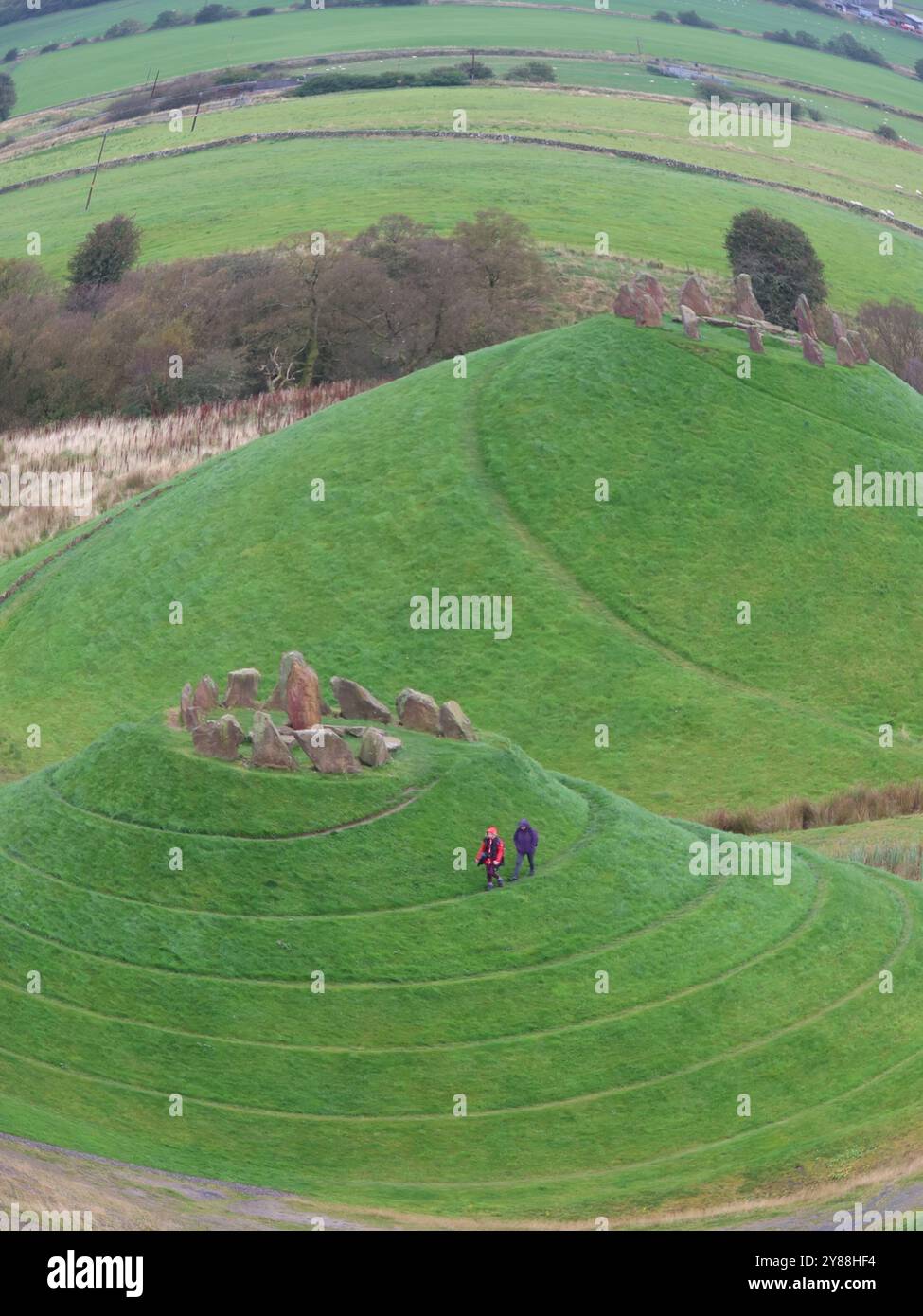 Deux figures sur un chemin en spirale qui serpente autour d'un des monticules qui représente la voie Lactée ; l'art du paysage Crawick Multiverse à travers un objectif fisheye. Banque D'Images