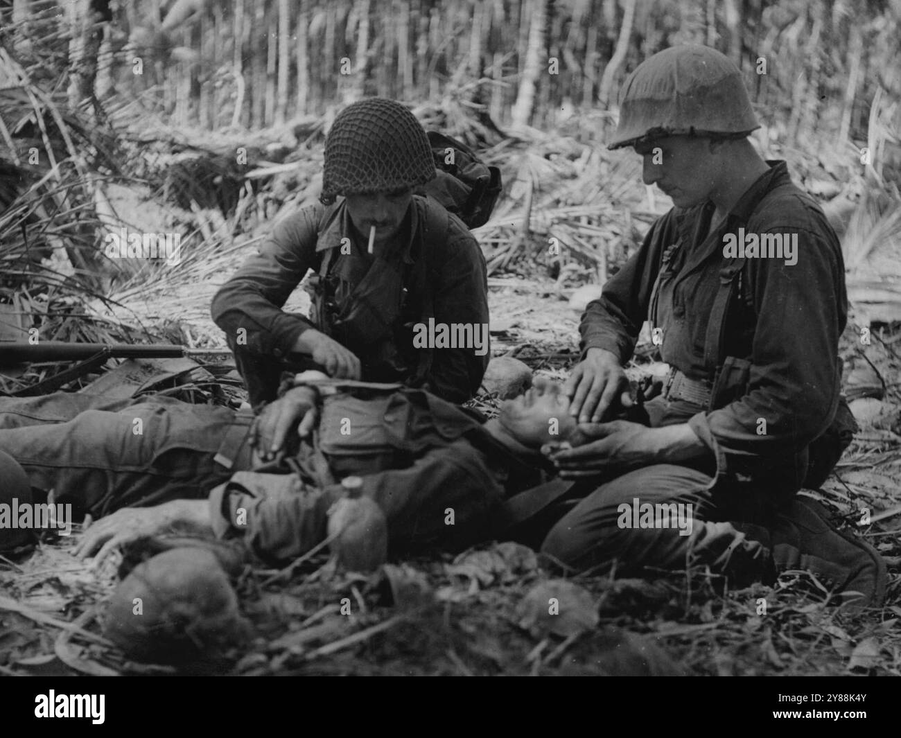 Les chars du général Stuart, habités en Australie et soutenus par l'infanterie australienne et américaine, attaquent Buna. Deux soldats américains pansent les blessures d'un australien. Cette photo a été prise pendant l'avance réelle. 28 janvier 1943. Banque D'Images