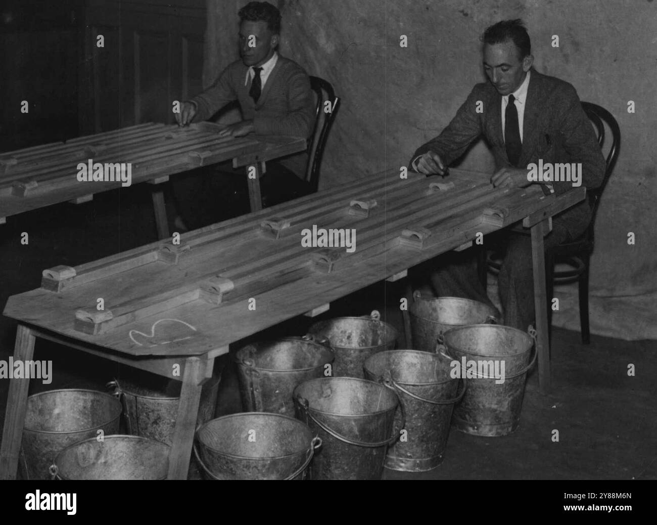 Tableaux ingénieusement construits qui sont utilisés dans le contrôle annuel des billes de loterie de l'État. Les plateaux tiennent environ 400 billes à la fois, les rainures sont marquées de 0 à 9, et les billes sont roulées par le "damier" le long de la rainure requise pour tomber à travers un trou dans les seaux en dessous. 6 novembre 1934. Banque D'Images