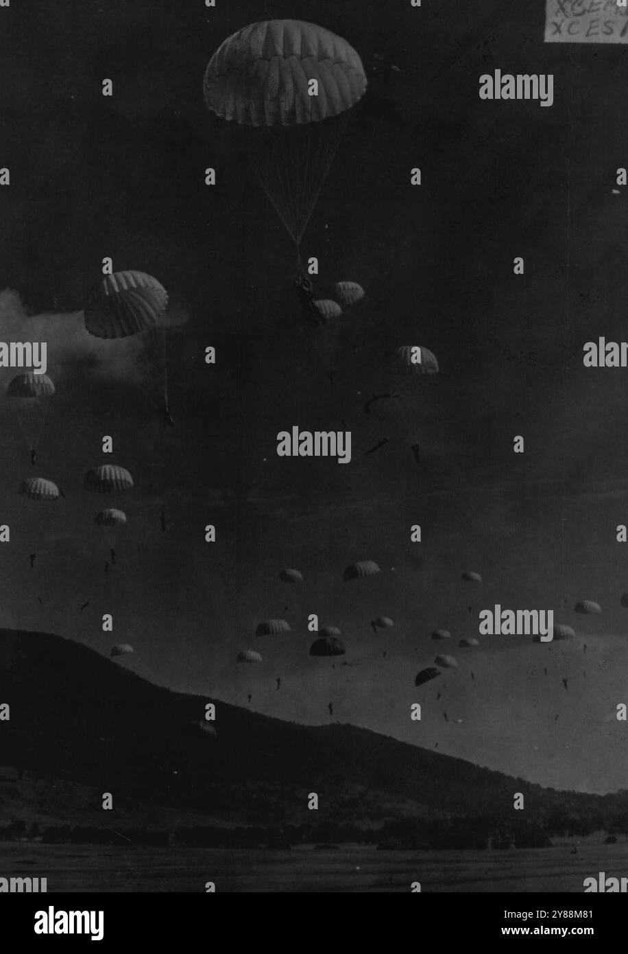 La « guerre » a éclaté dans un pays montagneux, à 32 kilomètres de Canberra hier, lorsque 38 parachutistes ont sauté pour venir en aide aux forces terrestres. Les unités combinées capturent une « colline ennemie » et un « général ennemi de Fantasia » près de Tharwa lors de l'exercice final d'une semaine de manœuvres de l'armée. Les parachutistes ont sauté de deux Dakotas de la RAAF, volant à 800 pieds. Atterrissant à quelques mètres de leur cible, ils se sont reformés et ont pris d'assaut à travers la vallée. Des tirs de mitrailleuses et des éclats de mortier de gerbeurs et de défenseurs résonnèrent à travers les collines. Le général « fantasien » capturé avait été contraint de fuir Canberra « bombardée d'atomes ». Novemb Banque D'Images