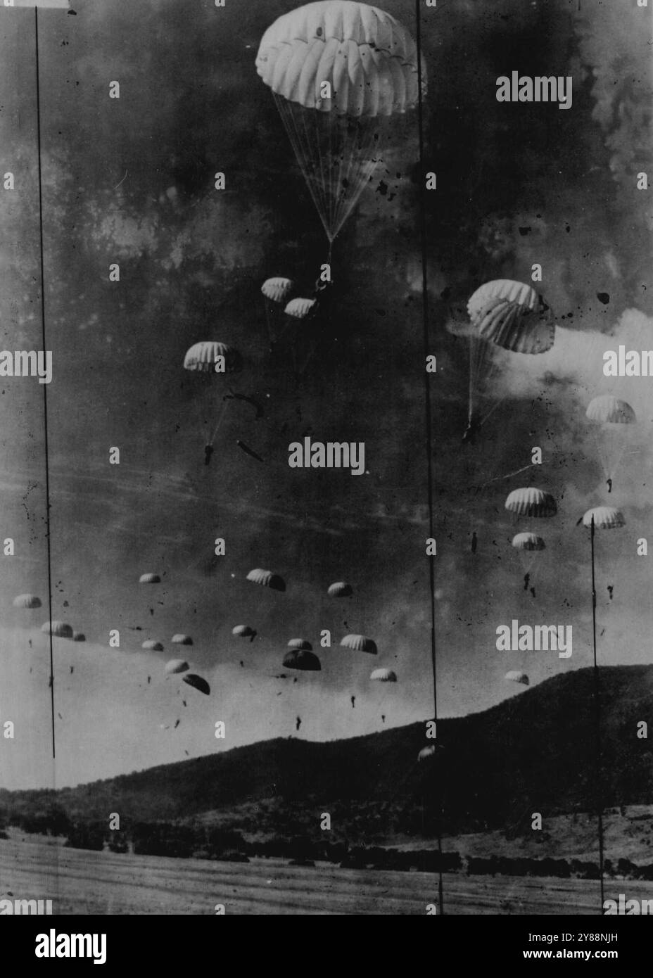 Des parachutistes atterrissant sur un « ennemi » ont tenu une piste d'atterrissage près de Tharwa, à 32 miles de Canberra, pendant les manœuvres de l'armée aujourd'hui. Les objets noirs pendants sous les sauteurs sont des armes automatiques. 22 novembre 1952. Banque D'Images
