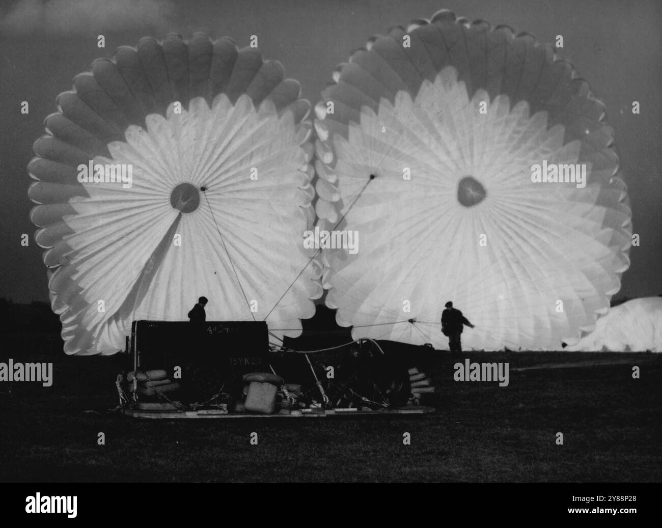 Spectral Guardians - Un pistolet et remorque, largué par un parachute lors d'exercices aériens anglo-américains à Watchfield, Berkshire, aujourd'hui, Mar. 6, est photographié ici sur le fond Ghostly formé par deux de ses parachutes. Notez l'emballage sous le pistolet et la remorque pour le protéger à l'atterrissage. L'exercice a été conçu pour renforcer la coopération anglo-américaine dans le soutien au sol. Y participaient des unités du commandement de Raf transport et de la 3e division aérienne des États-Unis. 06 mars 1951. (Photo d'Associated Press photo). Banque D'Images