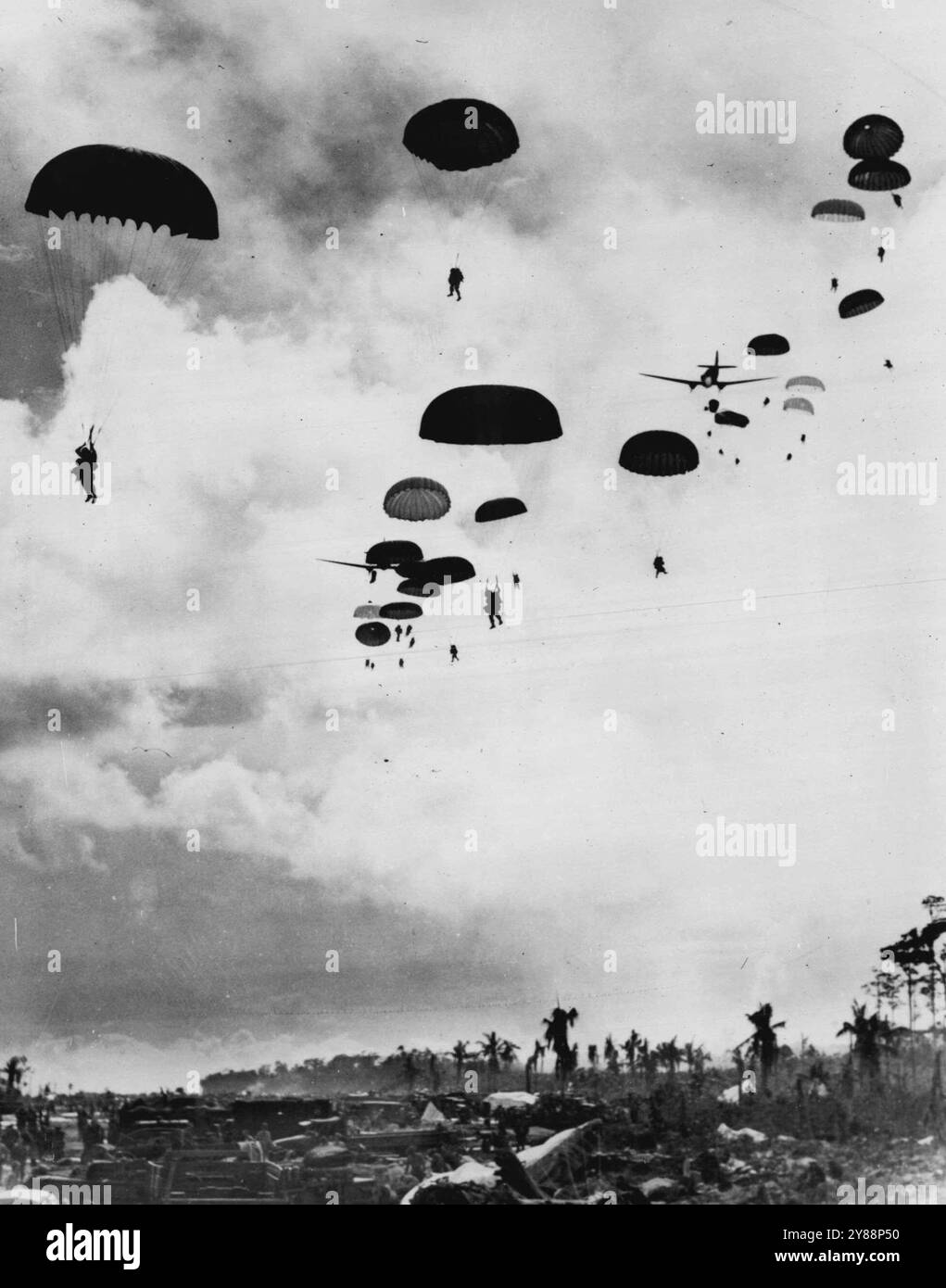 Des parachutistes américains débarquent sur l'île de Noemfoor - des renforts de parachutistes américains flottent depuis des avions de transport jusqu'à une tête de pont pour soutenir les débarquements amphibies alliés sur l'île de Noemfoor, à 800 miles (1280 kilomètres) des Philippines. Sur la tête de pont se trouvent des véhicules et des hommes de l'amphibie. 28 juillet 1944. (Photo du U.S. Office of War information Picture). Banque D'Images