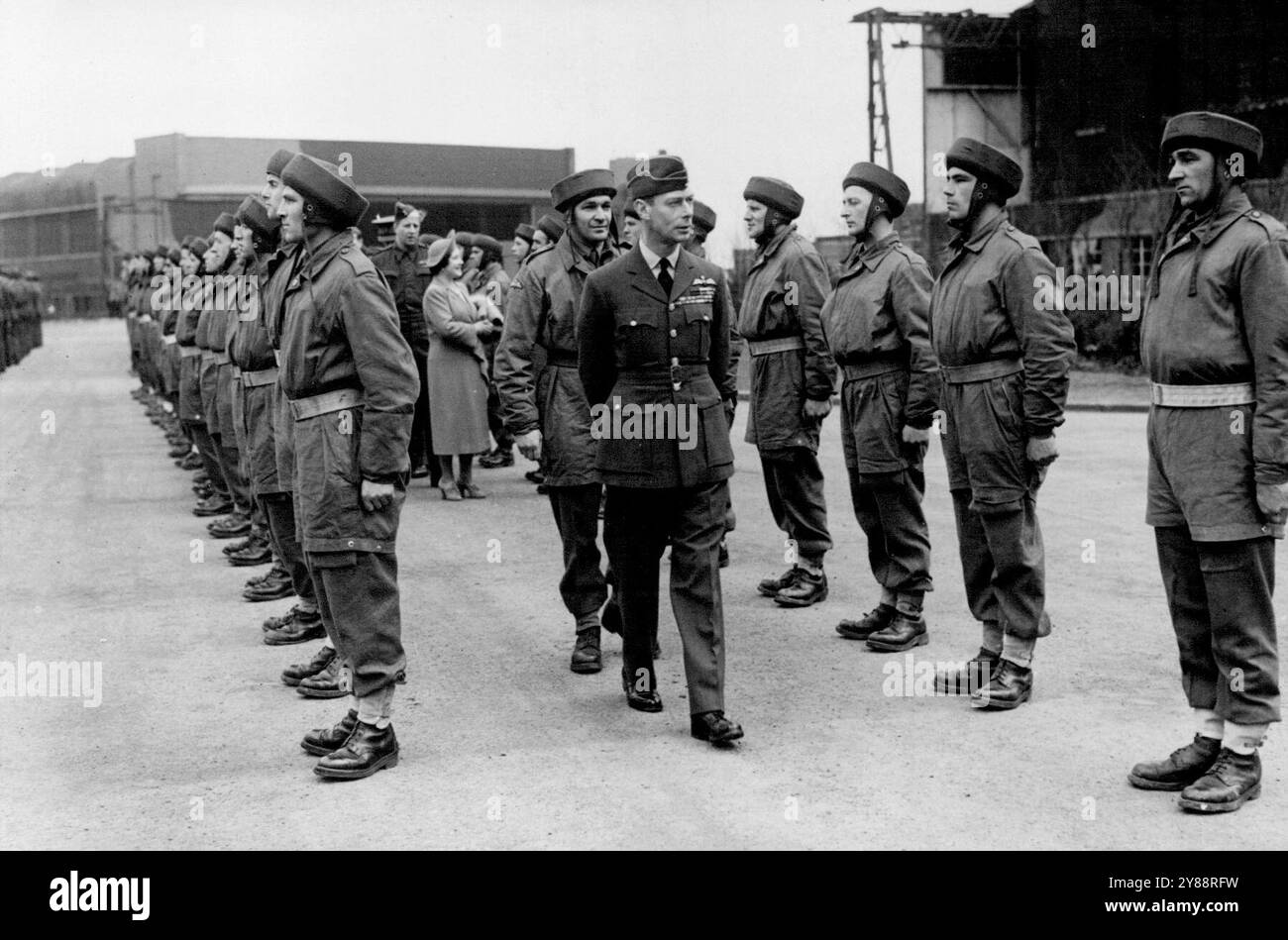 RAID parachutiste vu par le roi et la reine - le roi et la reine inspectant les troupes parachutistes à l'atterrissage. Lors d'une visite à un poste de bombardier R.A.F., le roi et la reine ont vu des troupes de parachutistes en action. Un vol de bombardiers noirs pointus survolait l'aérodrome et, un par un, des parachutes blancs et colorés s'ouvraient alors que des hommes larguaient de l'avion. Les hommes sont venus au double et se sont alignés pour être inspectés par le roi et la reine. 25 mars 1942. Banque D'Images