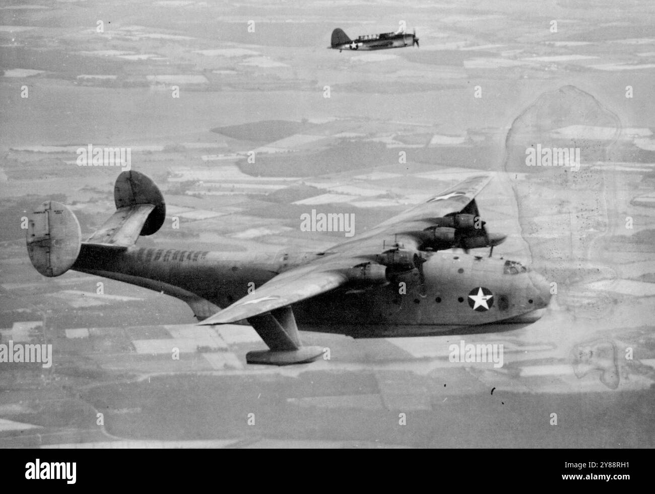 Giant Flying Boat in final test -- L'énorme navire cargo aérien de la Marine, le hydravion 'mars', est accompagné par un Brewster Buccaneer sur un vol de routine en tant que test final avant d'être retourné à la Marine par le ***** L. Martin Company, de Baltimore, constructeurs. Dans le test final, le 'mars' a volé 34 heures, 17 minutes sans s'arrêter, ce qui équivaut à un voyage de New York à Berlin. L'énorme hydravion sera utilisé par la marine pour transporter des fournitures essentielles et du personnel vers des théâtres de guerre lointains. 30 octobre 1943. (Photo d'Associated Press photo). Banque D'Images