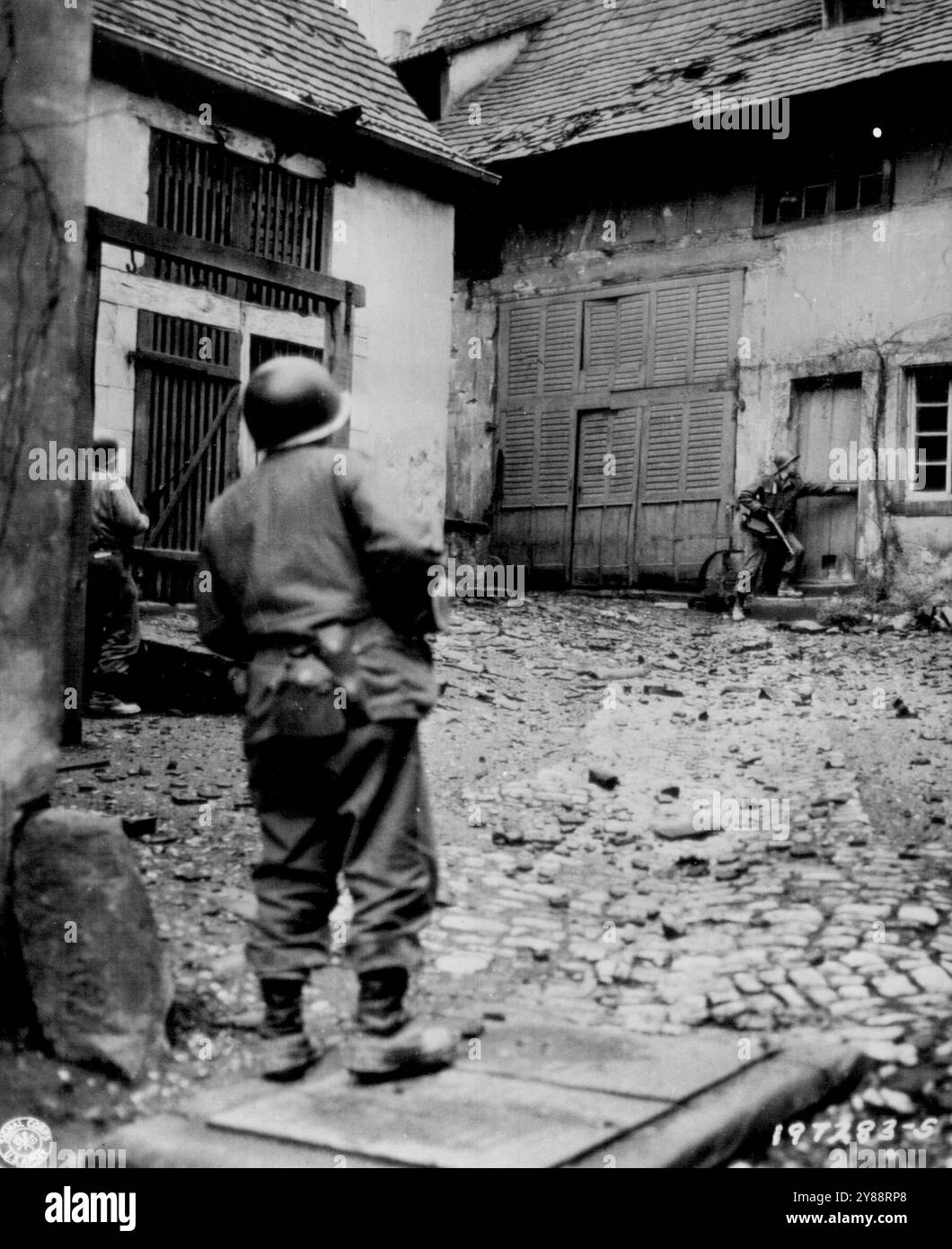 Sniper Hunt in French Town -- les Yanks se tiennent debout avec des fusils prêts comme un camarade alors qu'un camarade commence à ouvrir une porte pendant une chasse au sniper dans la ville française de NiederBrown sur le front de la septième armée américaine. 20 décembre 1944. (Photo de AP Wirephoto). Banque D'Images