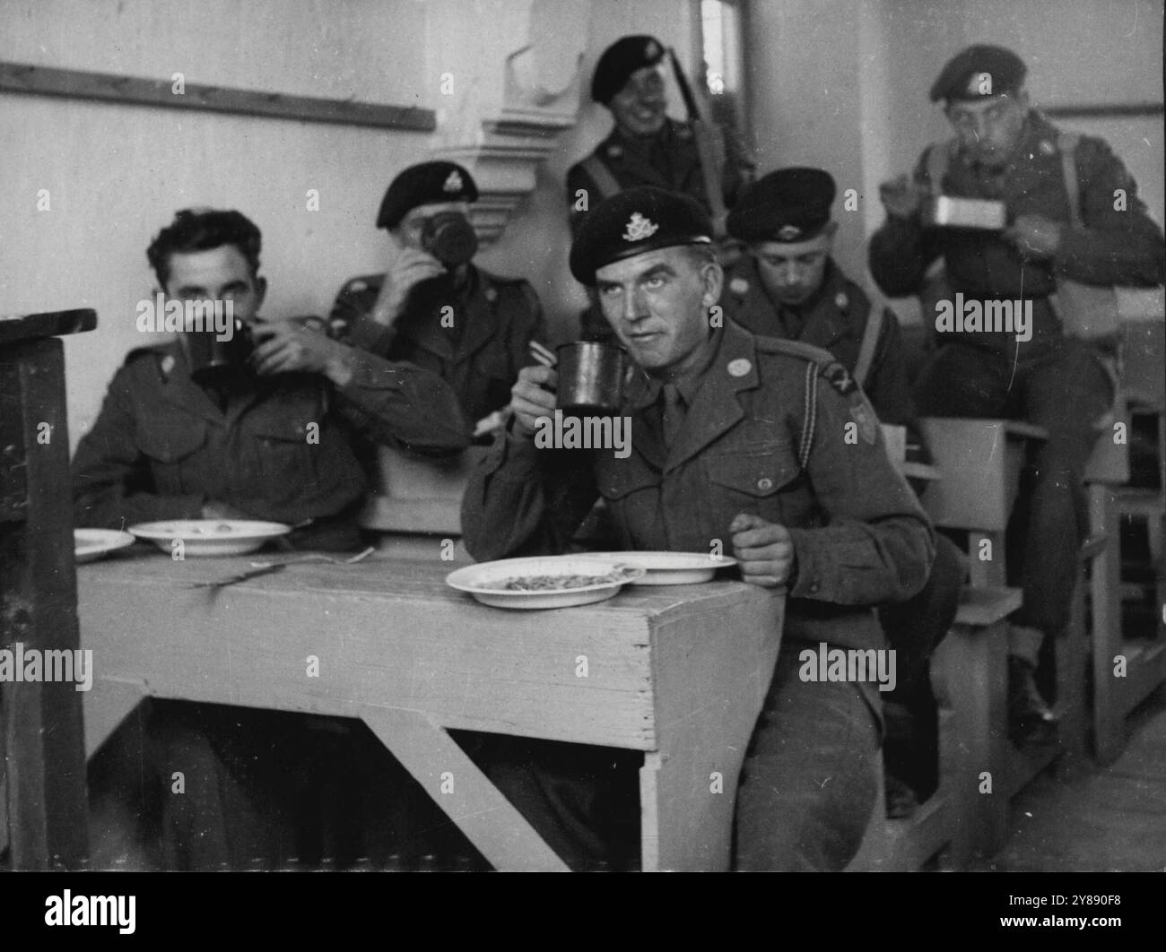 Les troupes chypriotes prennent le contrôle de l'école fermée - les hommes du South Stafford Shire Regiment mangent leur petit déjeuner sur les pupitres des écoliers de l'école Samuel de Nicosie, qui a été fermée sur ordre du gouverneur, le maréchal Sir John Harding, à la suite de manifestations indisciplinées des écoliers. Les enfants, indisciplinés, prennent toute leur part des manifestations et des émeutes contre les troupes britanniques. 18 novembre 1955. Banque D'Images