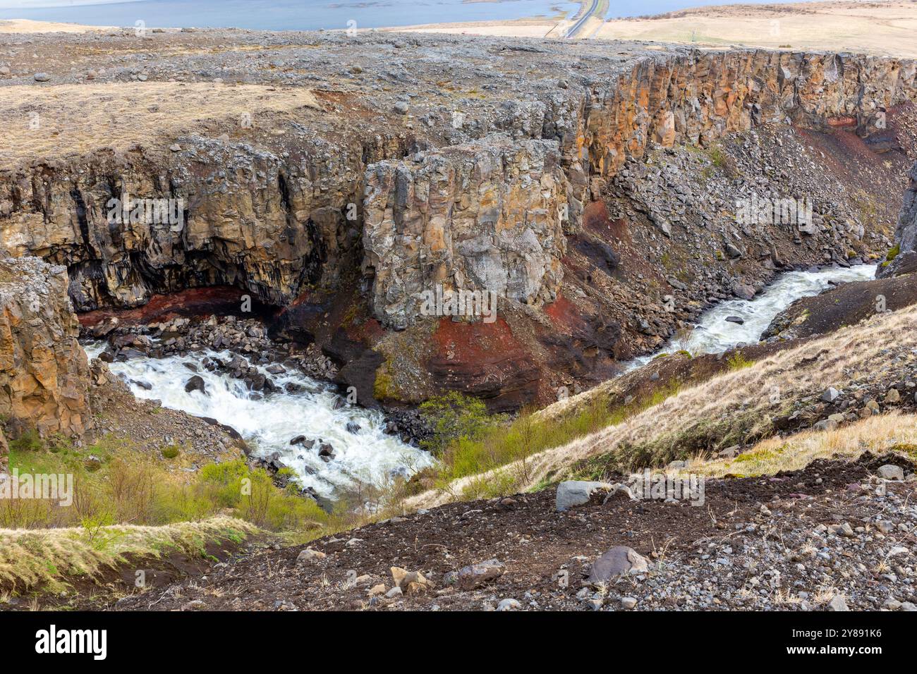 Vallée de la rivière Hengifossa à Fljotsdalshreppur, dans l'est de l'Islande avec des formations rocheuses rouges et brunes, des falaises et le lac glaciaire Lagarfljot en arrière-plan. Banque D'Images