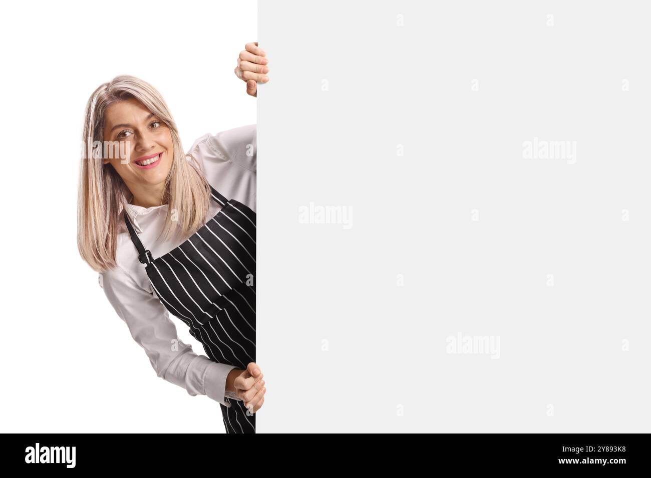 Barista féminin debout derrière un panneau blanc et souriant isolé sur fond blanc Banque D'Images