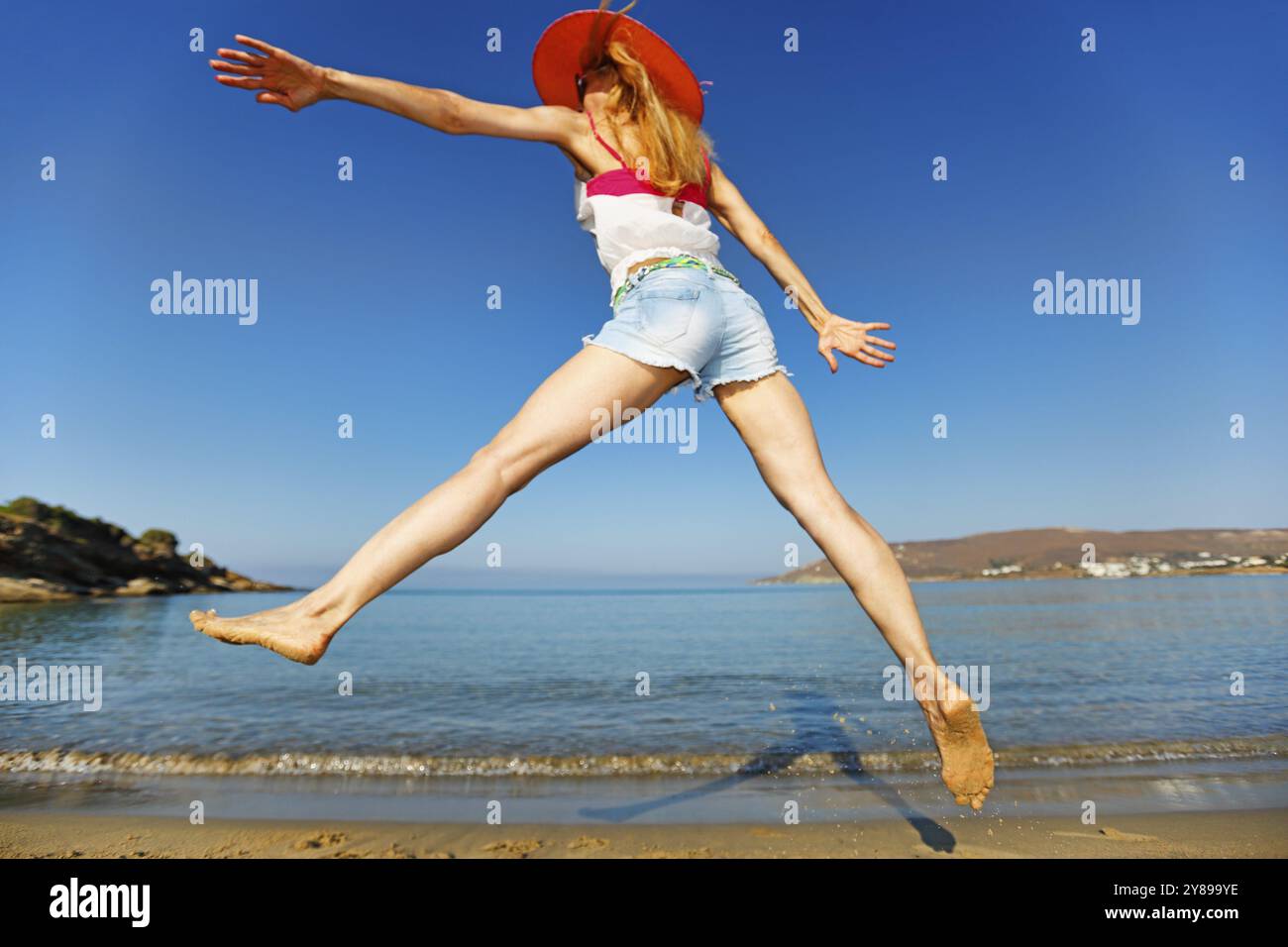 Une femme saute à la plage Banque D'Images