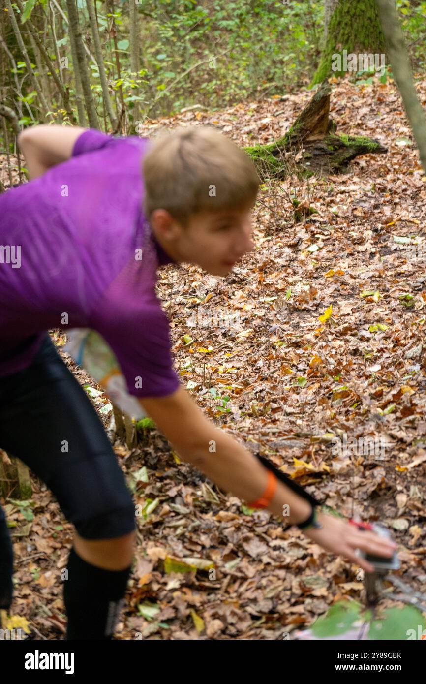 Un homme frappant au point de contrôle de la course d'orientation de près. Image floue avec un mâle dans la vérification de forêt à un point de contrôle. Mise au point sélective Banque D'Images