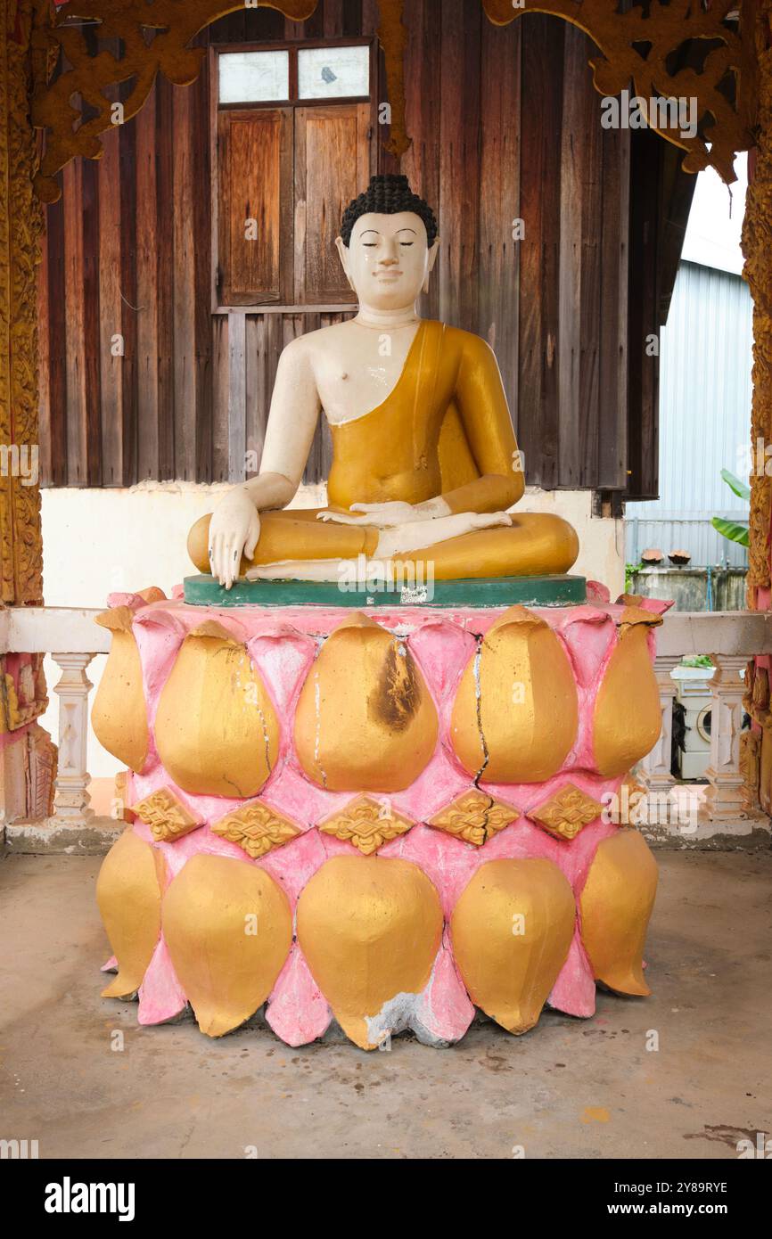 Une figure de Bouddha assise sur des feuilles de lotus dorées et roses, des fleurs. Au Wat That Khao à Vientiane, Laos Banque D'Images