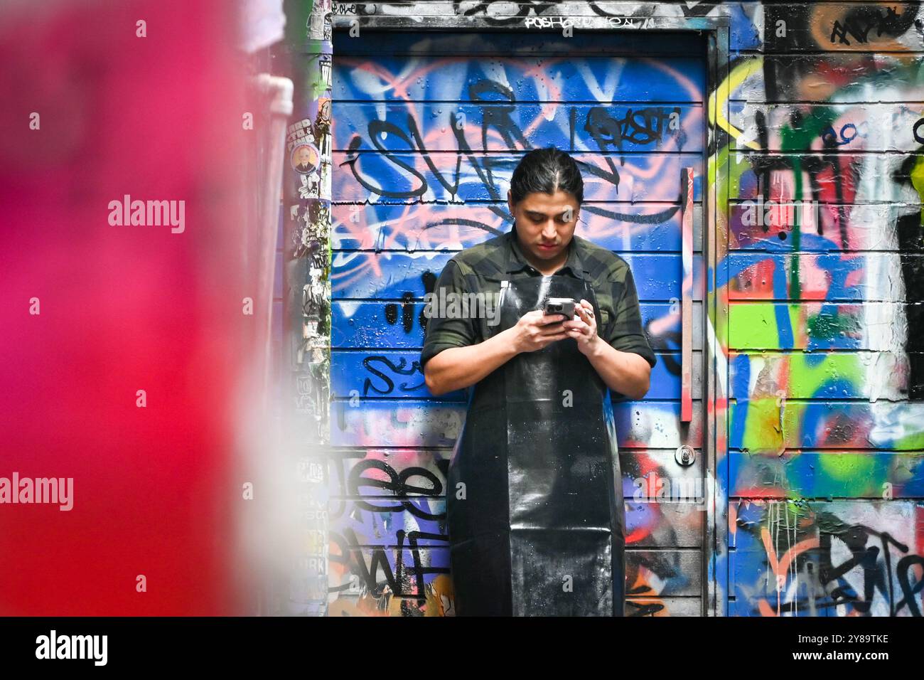 Un homme vérifie son téléphone dans Hosier Lane, une célèbre rue graffiti à Melbourne, en Australie Banque D'Images