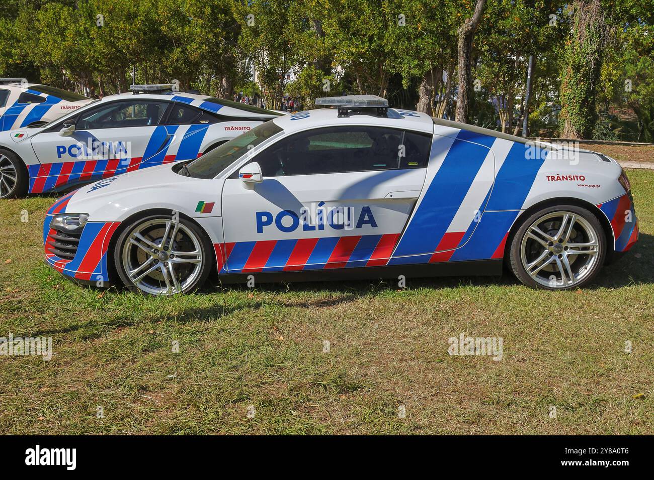 Voiture de police portugaise blanche avec des rayures bleues et rouges garée sur l'herbe par une journée ensoleillée Banque D'Images