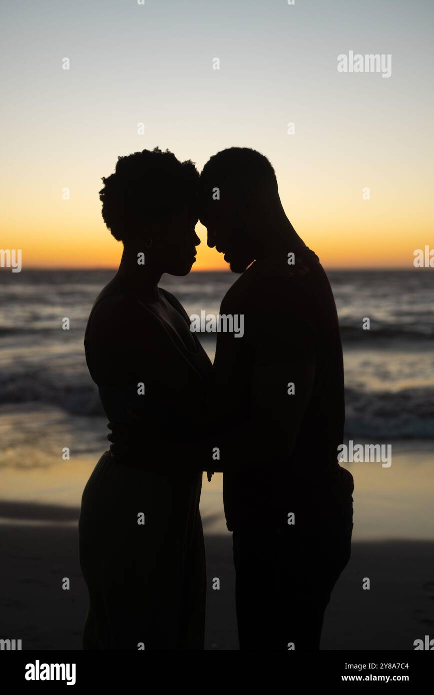 Un couple afro-américain silhouetté partage un moment tendre au coucher du soleil, avec un espace de copie Banque D'Images