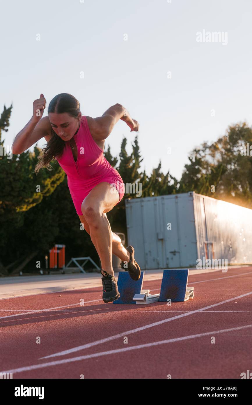 Athlète féminine sprintant hors de blocs Banque D'Images