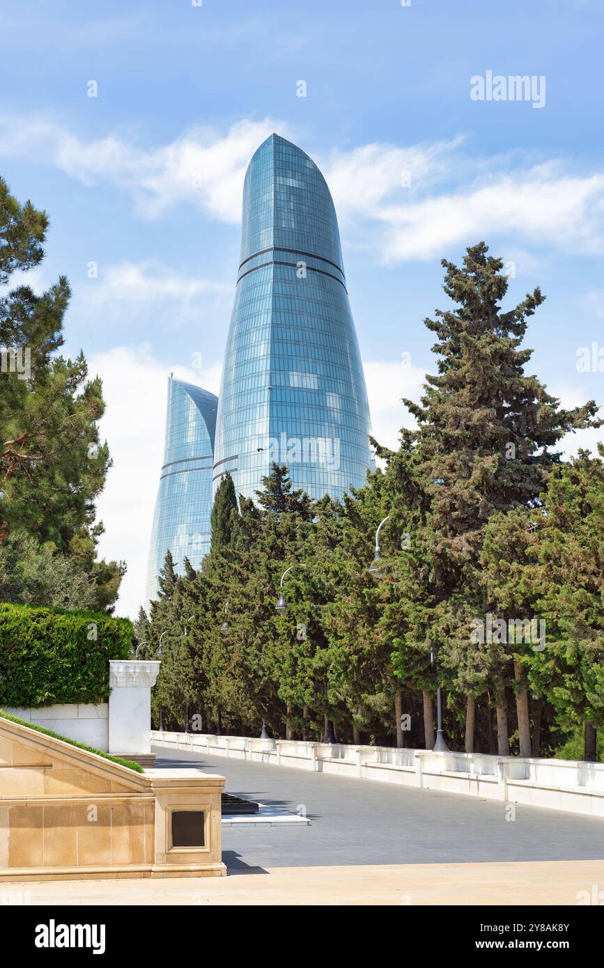 Depuis Martyrs Lane, les emblématiques tours de flammes de Bakou, en Azerbaïdjan, s'élèvent majestueusement contre un ciel bleu clair, leur forme rappelant les flammes, tandis que les arbres au premier plan améliorent le paysage urbain Banque D'Images