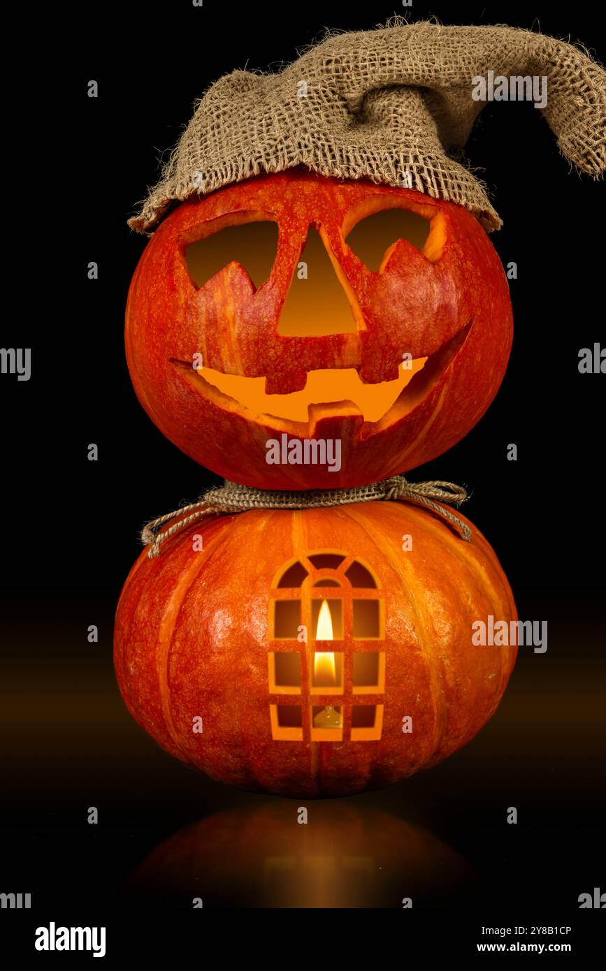 Un affichage créatif de deux citrouilles empilées, l'une avec un visage heureux et une fenêtre, illuminée de l'intérieur, parfait pour les célébrations d'Halloween ceci Banque D'Images