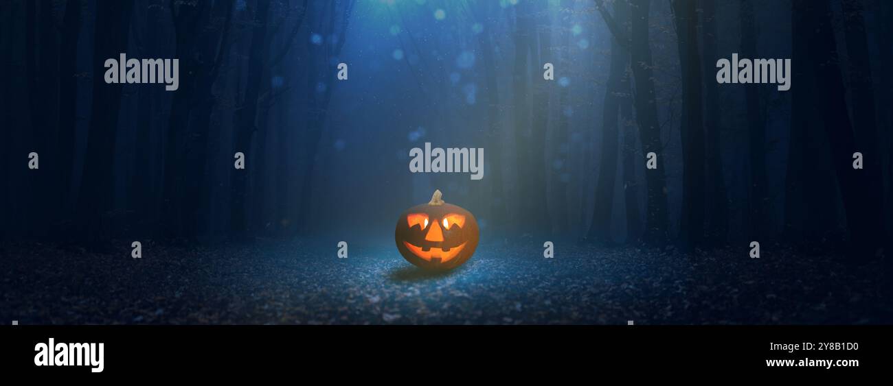 Une lanterne unique illumine la forêt sombre, créant une atmosphère étrange d'Halloween avec son visage éclatant et sa lumière enchanteresse. Banque D'Images