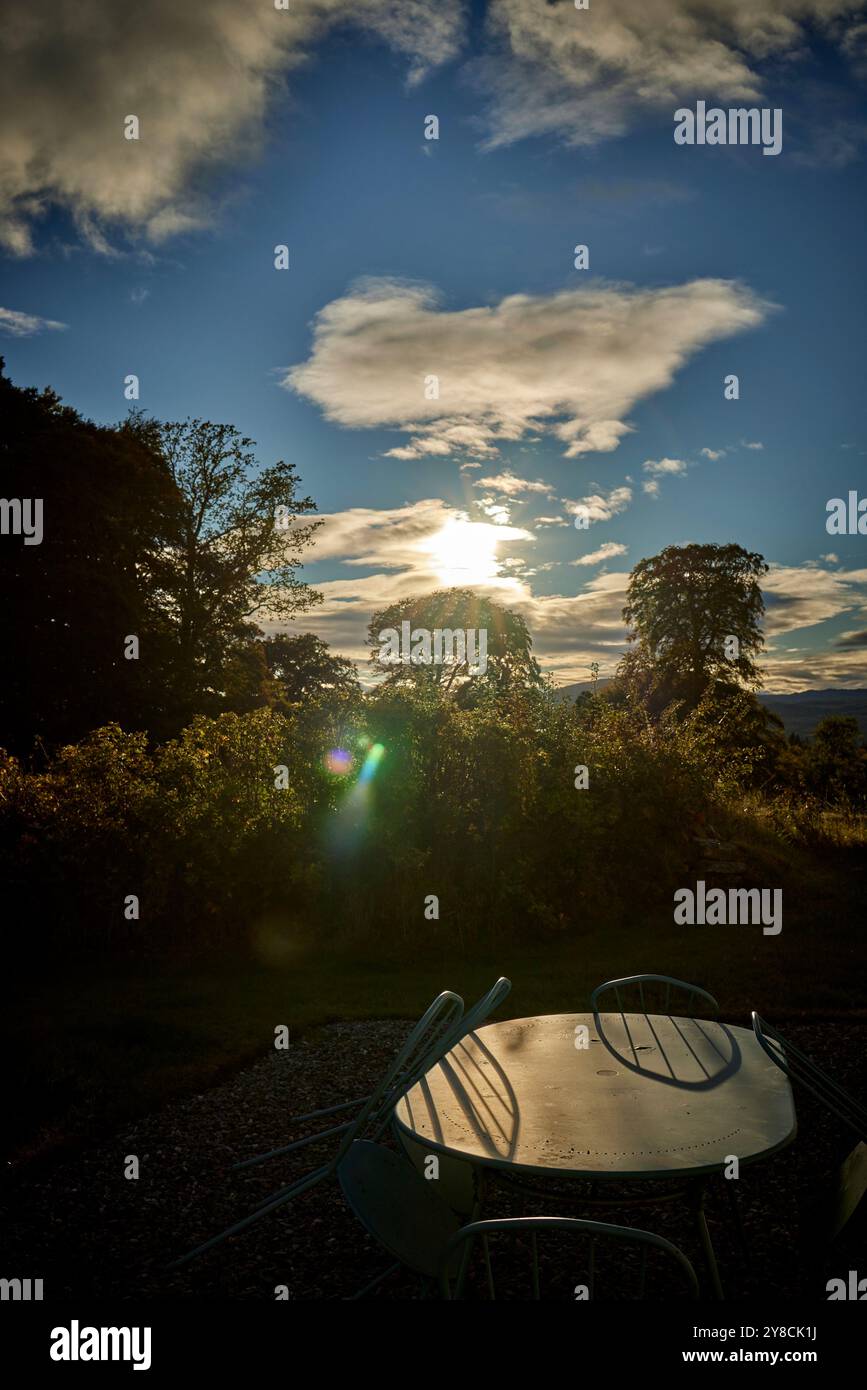 Le coucher du soleil de septembre jette des ombres sur les chaises et la table extérieures vacantes en Écosse Banque D'Images