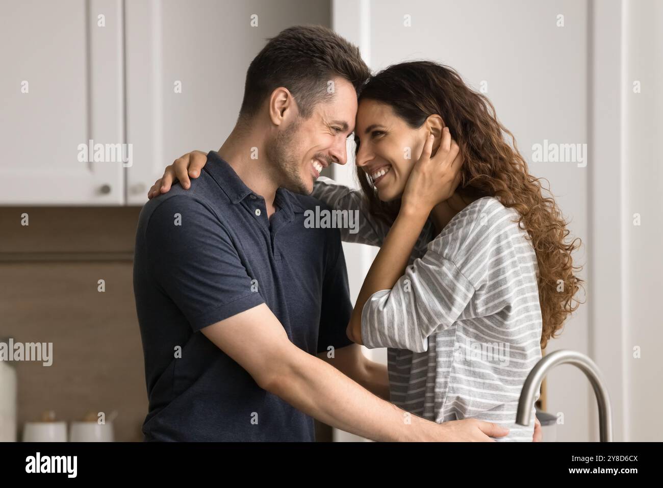 Joyeux couple romantique jeune debout près, riant dans la cuisine Banque D'Images