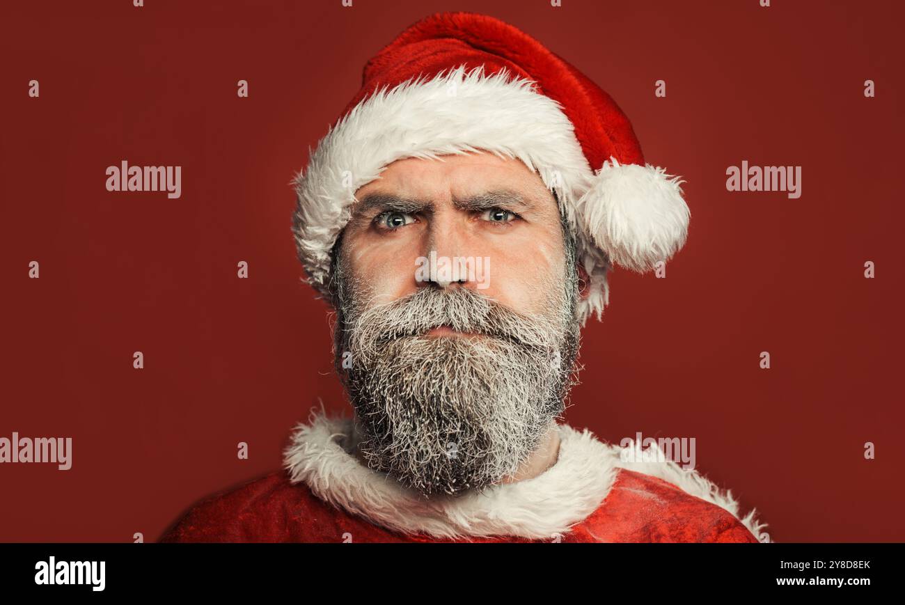 Noël. Gros plan portrait du Père Noël sérieux avec la barbe gelée. Homme barbu en chapeau de Père Noël et costume de Noël. Vacances en famille. Joyeux Chri Banque D'Images