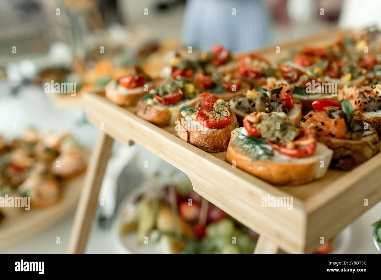 Une superbe sélection de canapés gastronomiques est disposée sur un plateau en bois, mettant en valeur un mélange coloré de garnitures lors d'une réunion sociale animée, invitante Banque D'Images