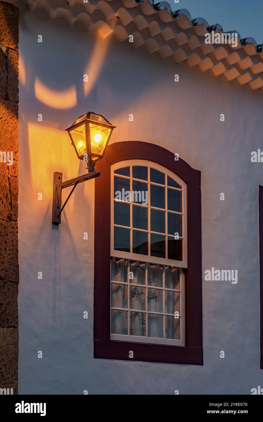Fenêtre et façade d'une ancienne maison de style colonial illuminée par une lanterne la nuit à Tiradentes, Minas Gerais, Brésil Banque D'Images Fenêtre et façade d'une ancienne maison de style colonial illuminée par une lanterne la nuit à Tiradentes, Minas Gerais, Brésil Banque D'Images