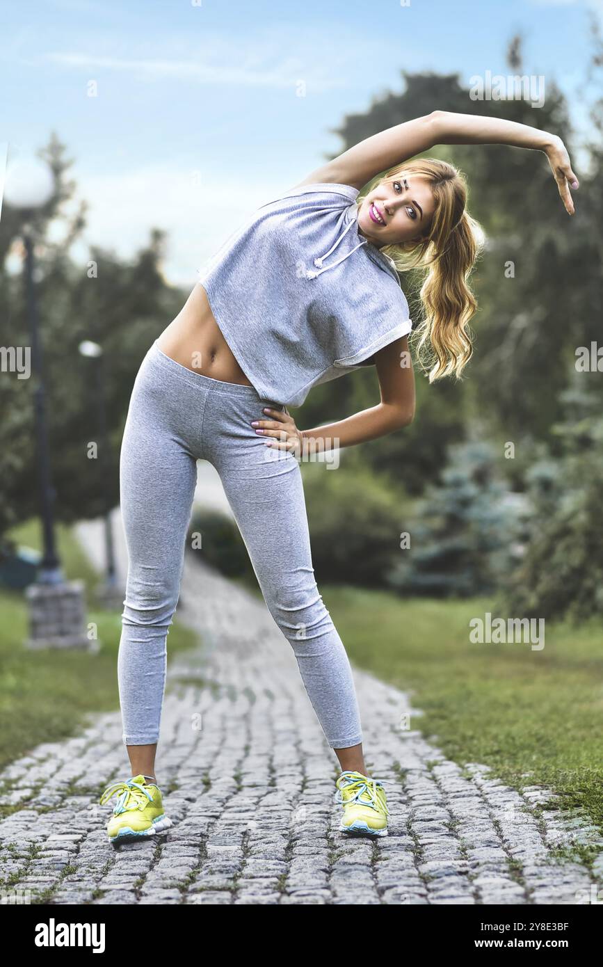 Athlète s'étirant avant un entraînement sportif dans la rue dans le parc de la ville Banque D'Images