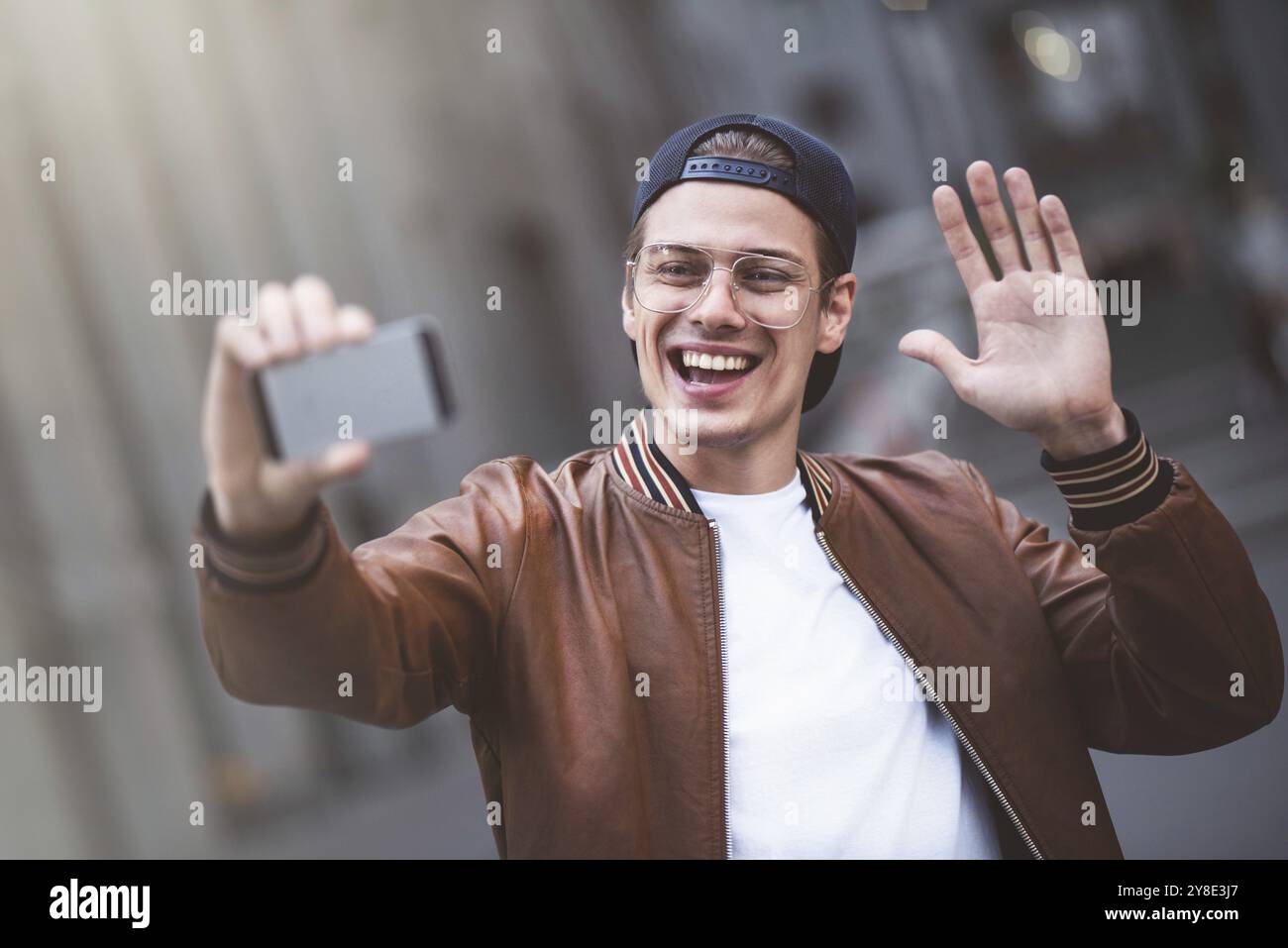 Selfie mania excité jeune gars fait selfie sur une caméra. Il porte des vêtements tendance décontractés et se rabat en arrière Banque D'Images