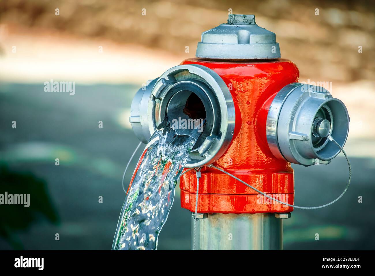 Gros plan de l'eau s'écoulant de la bouche d'incendie rouge ouverte Banque D'Images