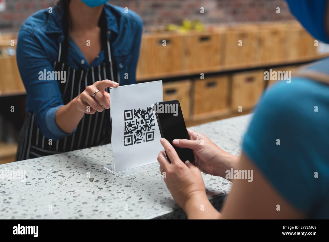 Milieu de section de deux femmes caucasiennes une prenant une photo du code qr sur le comptoir Banque D'Images