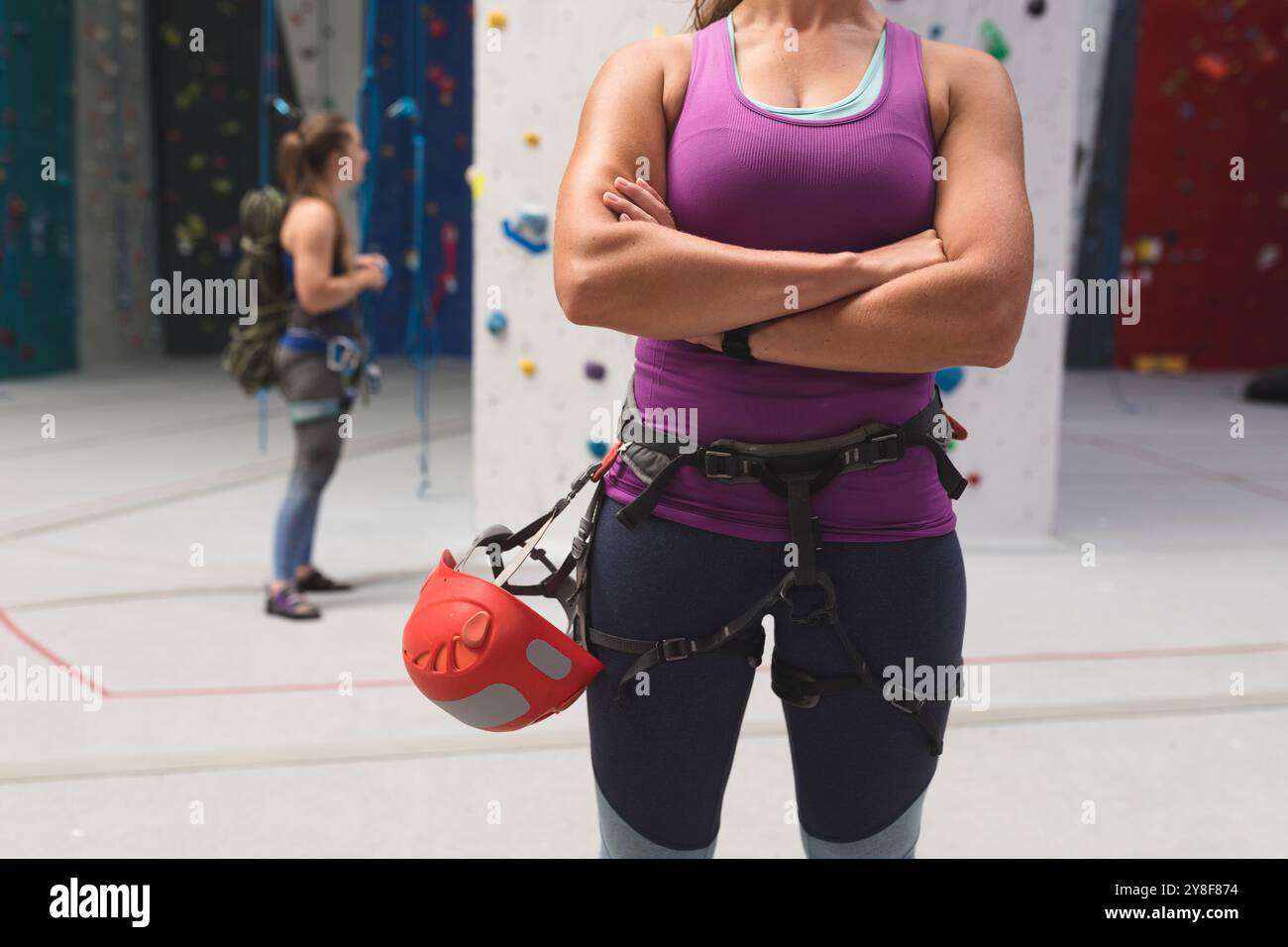 Section médiane de femme caucasienne avec casque se préparant à grimper au mur d'escalade intérieur Banque D'Images