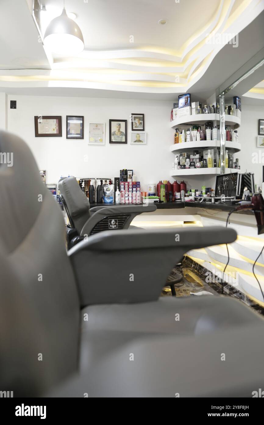 Vue rapprochée de l'intérieur du salon de coiffure avec chaises et certificats encadrés sur le mur. Banque D'Images